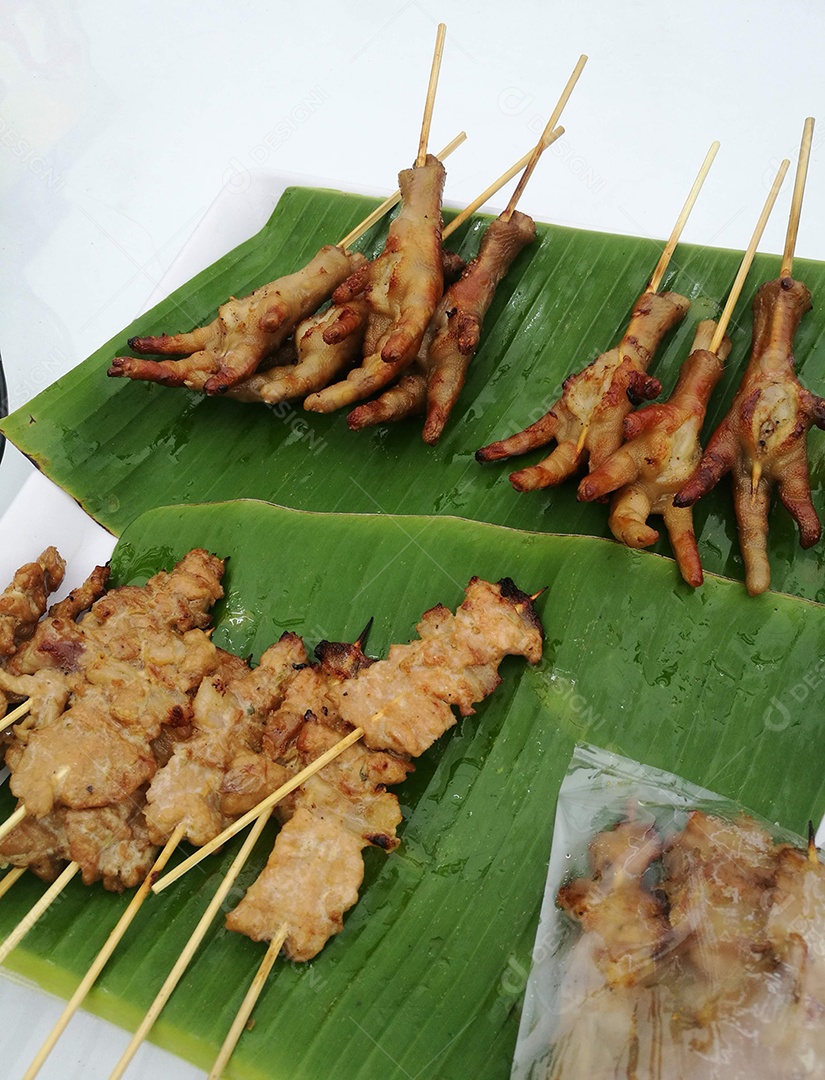 Espetinho de pés de galinhas sobre folha verde de bananeira