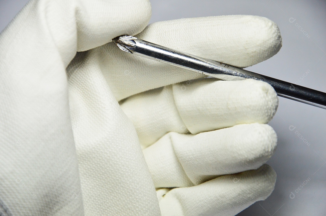 Mão com luva branca segurando chave cromada