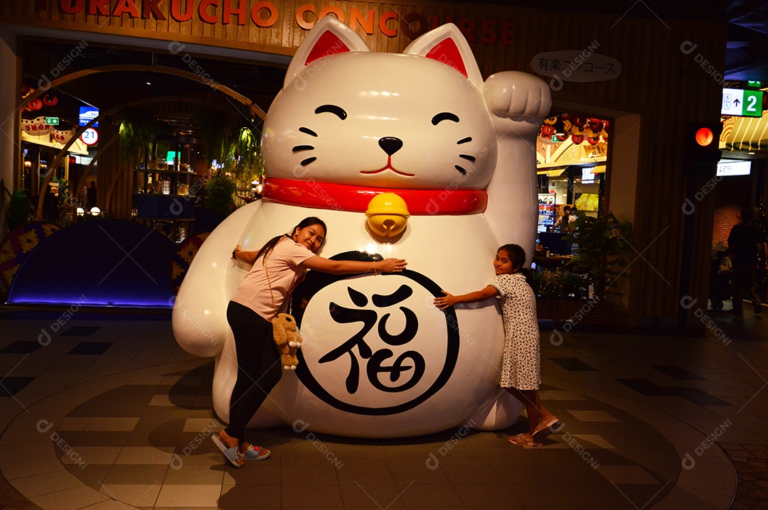 Crianças japonesas abraçando estátua de gato gigante