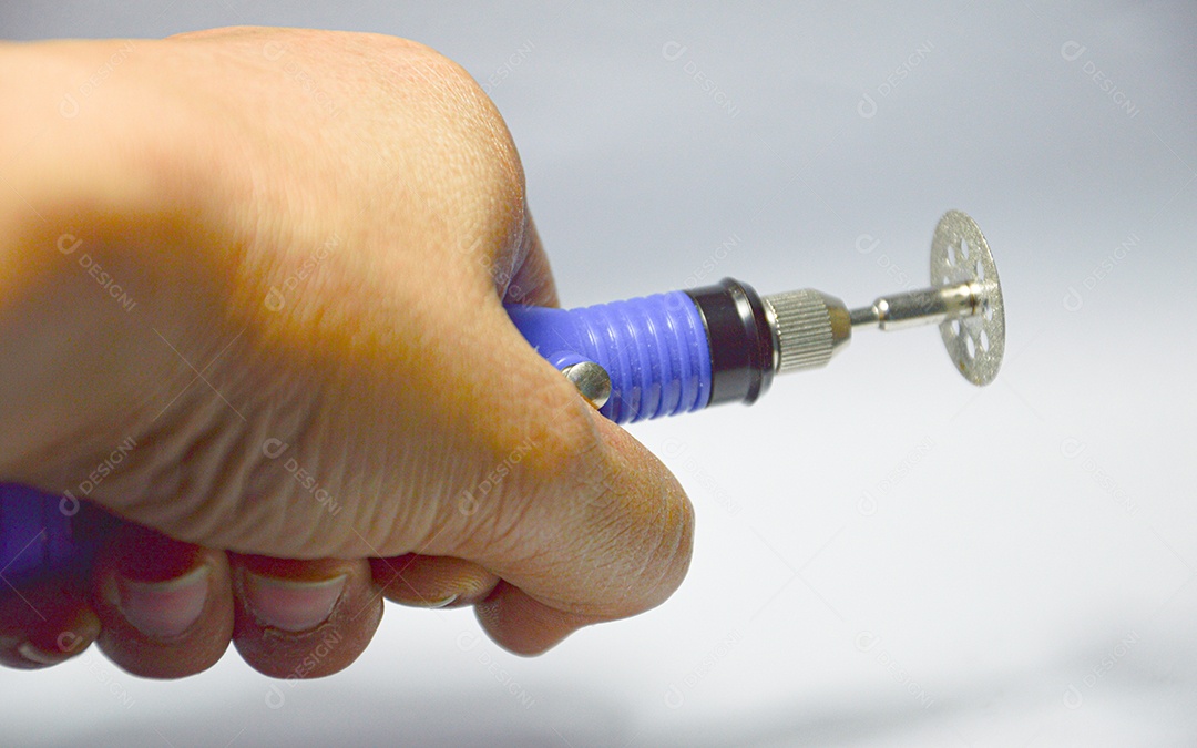 Mão segurando maquininha elétrica de lixar