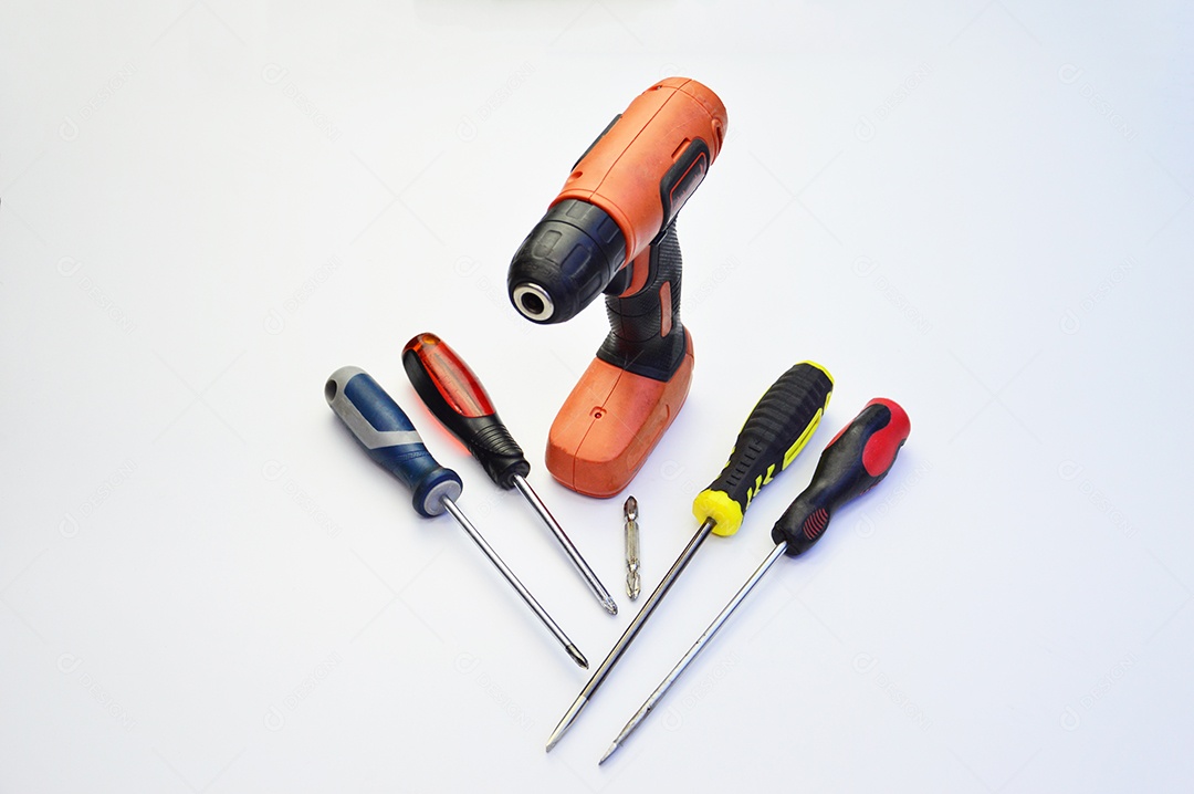 Furadeira elétrica e chaves de fenda em fundo branco