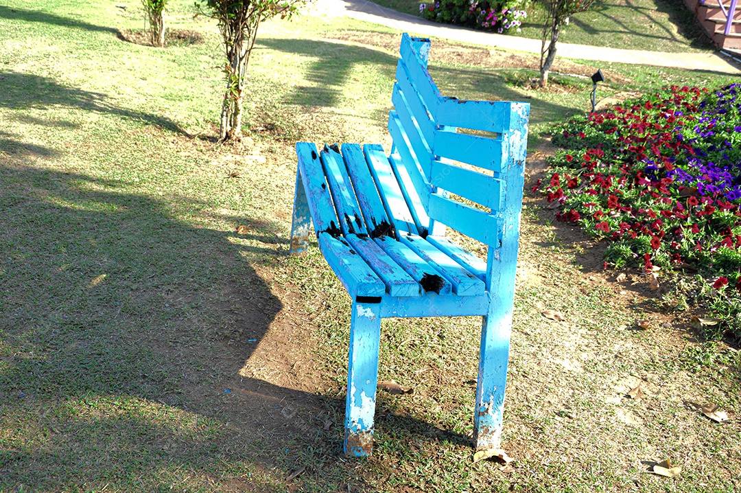 Banco de madeira azul quebrado no gramado
