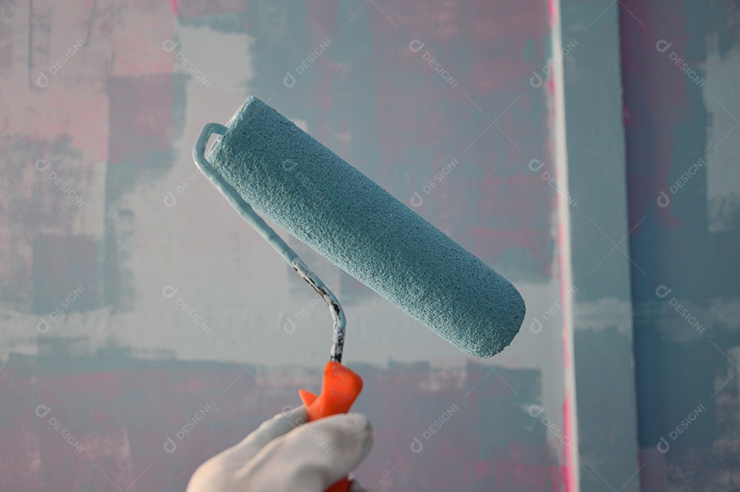 Pintor com rolo de tinta pintando parede