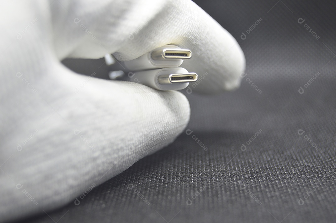 Mão segurando cabo adaptador em fundo preto