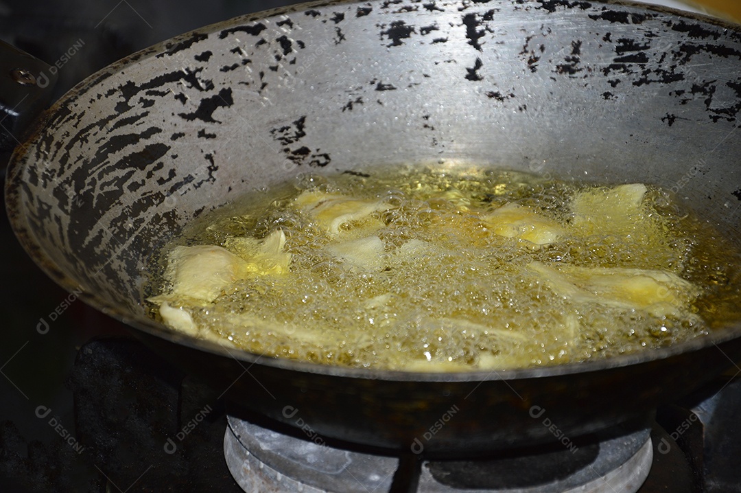 Panela com óleo quente fritando bananas