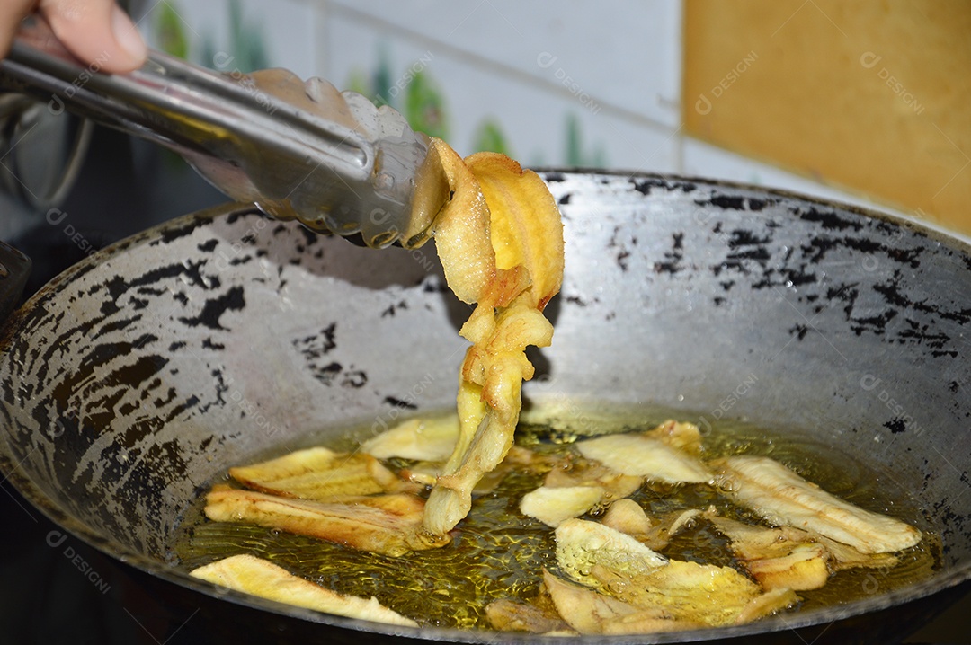 Panela com óleo quente fritando bananas