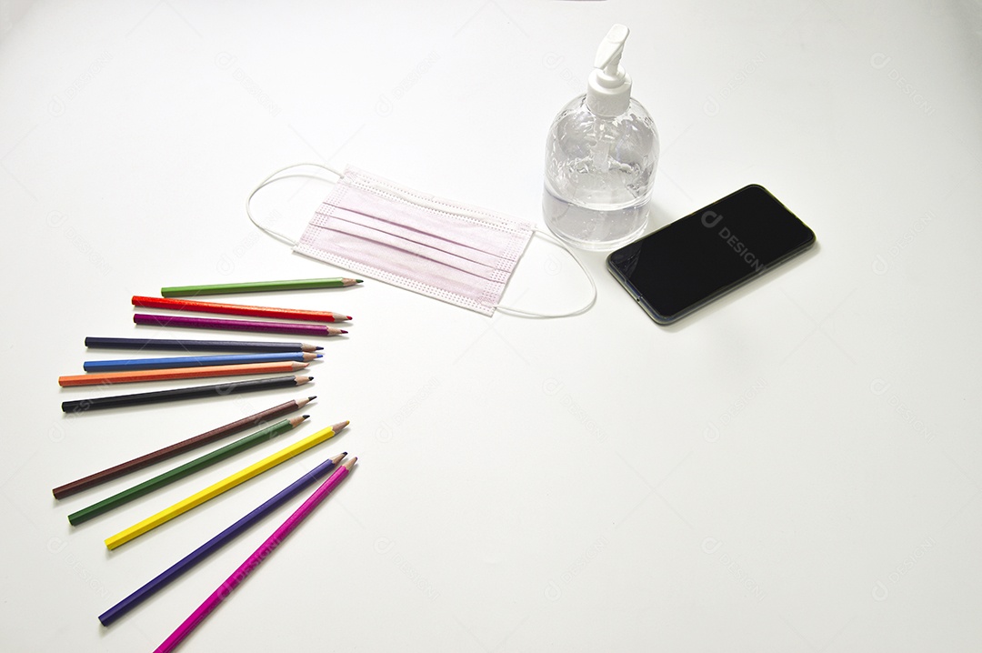 Lápis coloridos e máscara de proteção em fundo branco