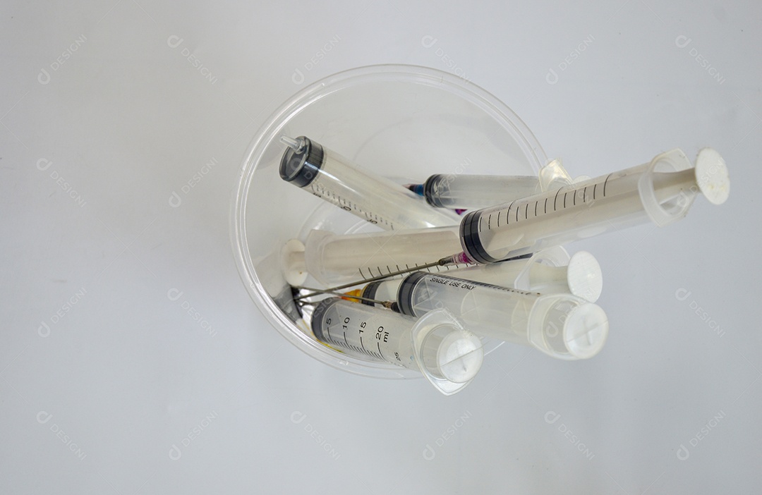 Seringas usadas colocadas em um recipiente branco transparente