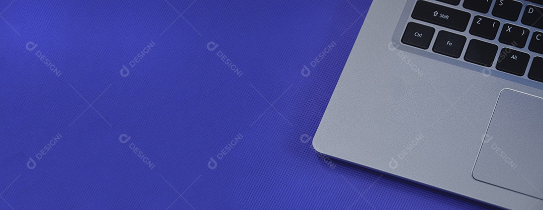 Vista esquerda de um laptop branco sobre um fundo azul.