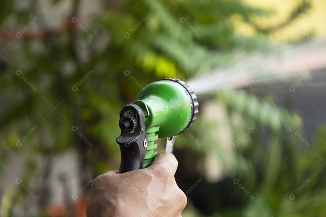 Um jardineiro usando spray de água para regar as plantas