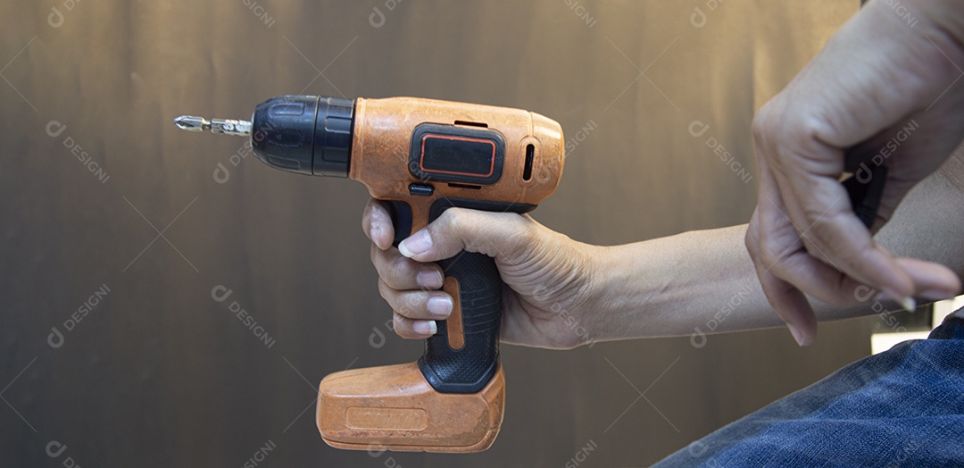 Artesão que está segurando uma chave de fenda elétrica laranja