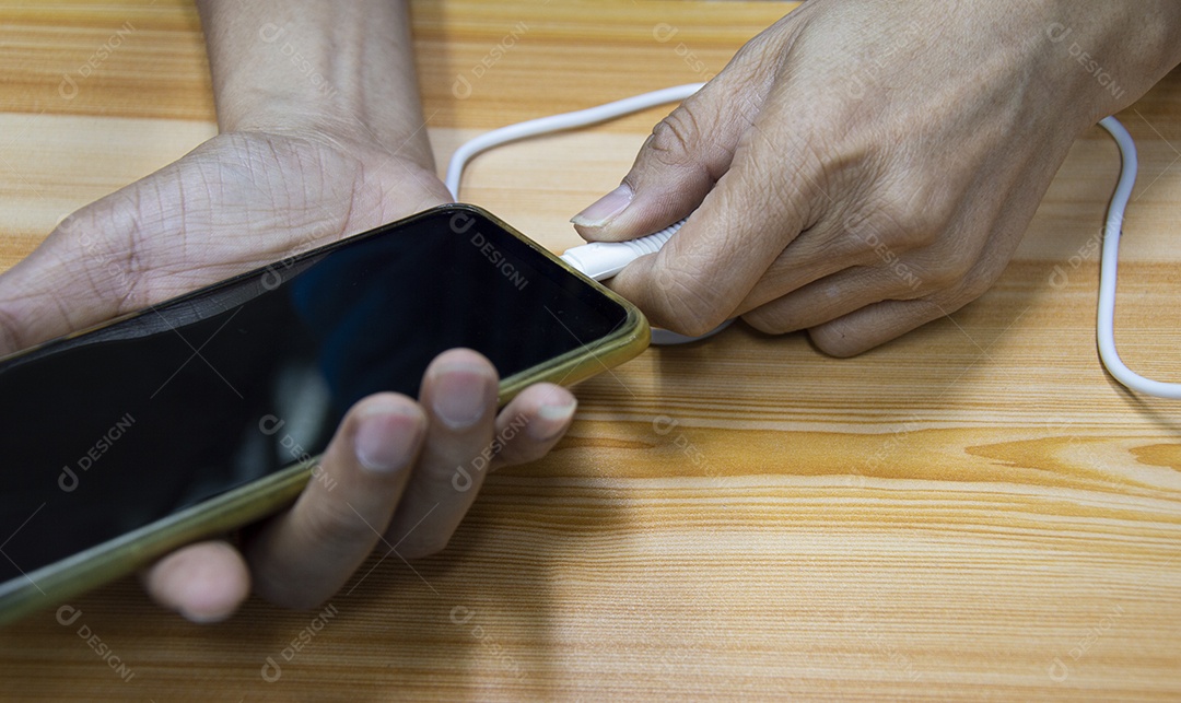 Mão masculina conectando o carregador de bateria de um smartphone