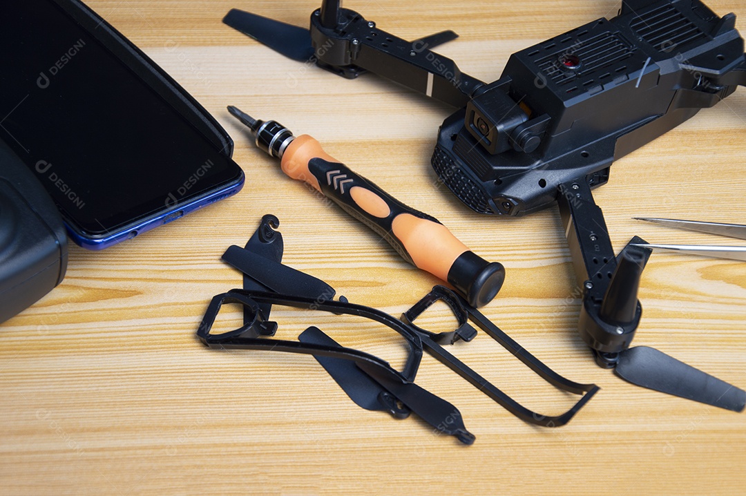 Reparando um pequeno drone de chave de fenda em cima da mesa com várias ferramentas