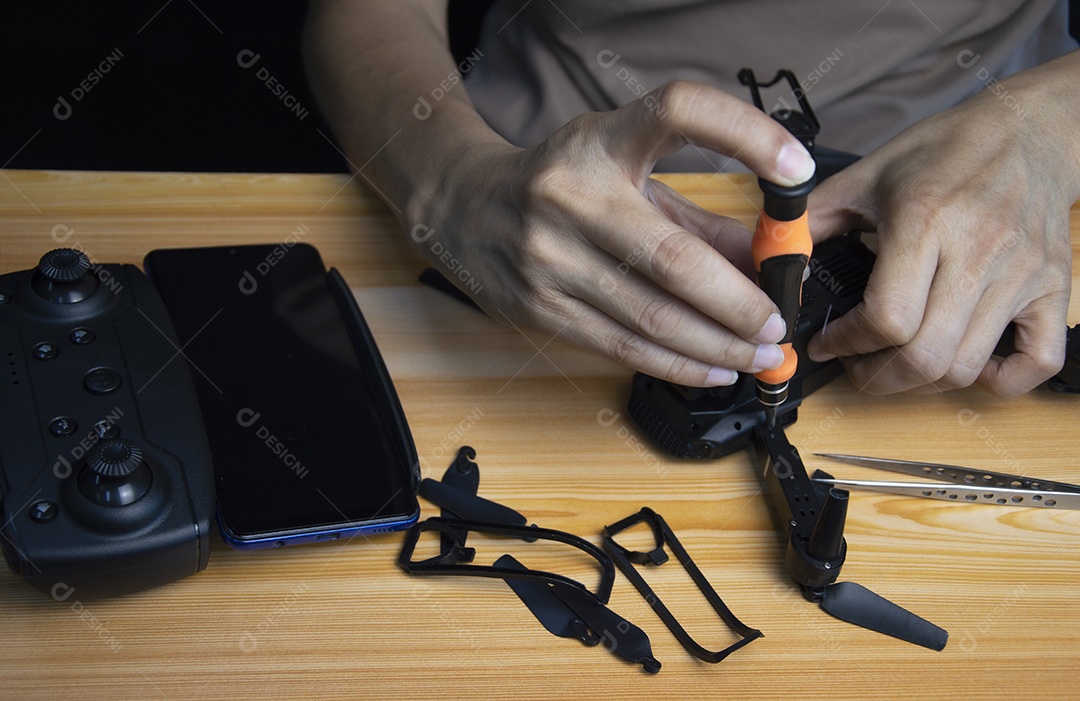 Reparando um pequeno drone de chave de fenda em cima da mesa com várias ferramentas