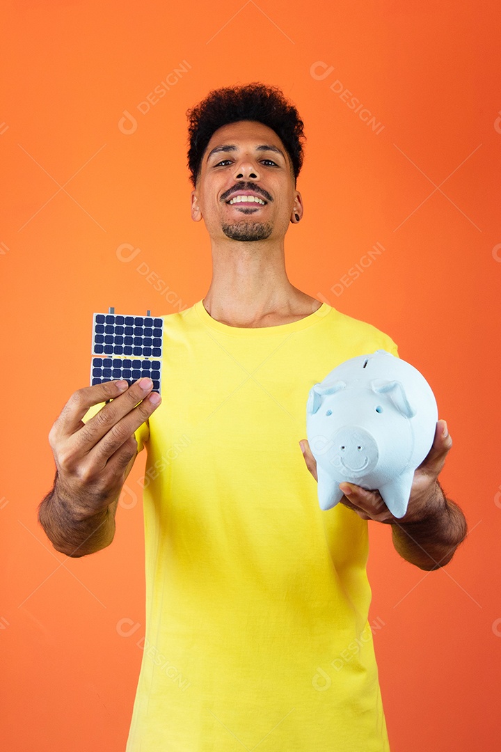 Homem negro segurando um cofrinho e painel solar isolado em laranja.
