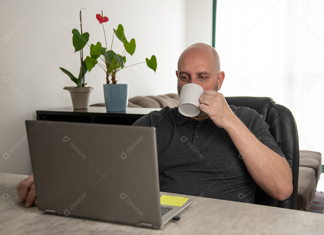 Homem tomando café trabalhando em casa