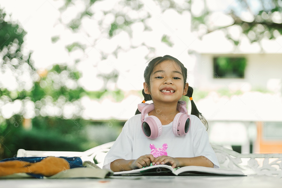 Garotinha sentada na mesa com materiais na mochila