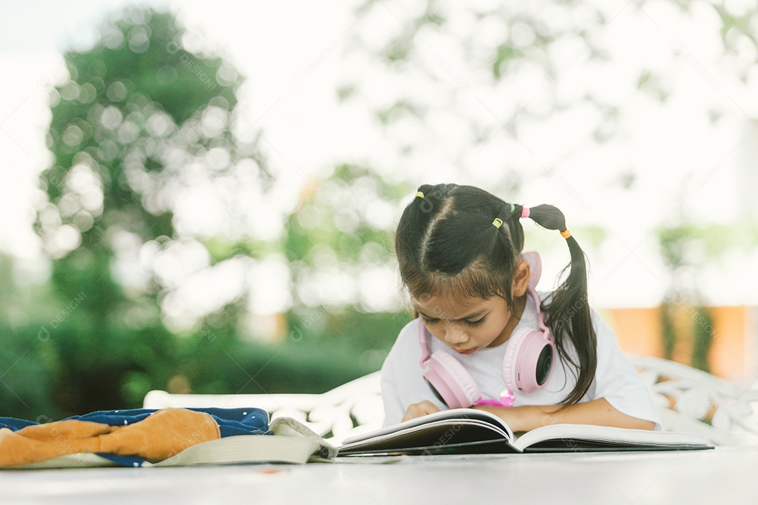 Garotinha sentada na mesa com materiais na mochila