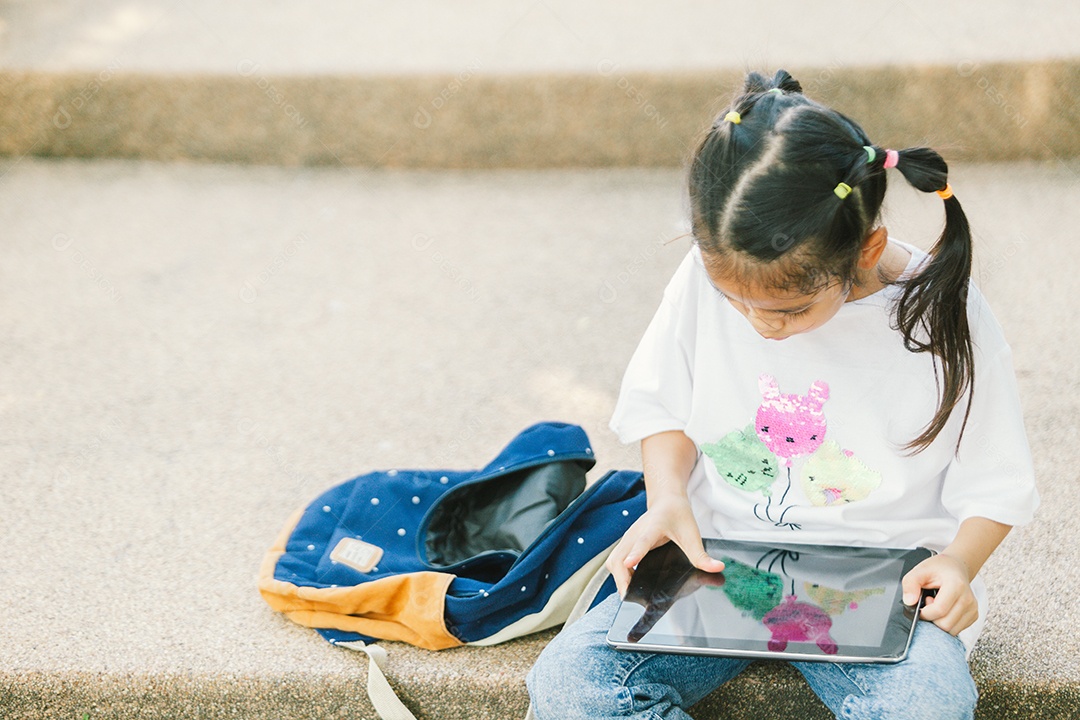 Garotinha sentada usando tablet