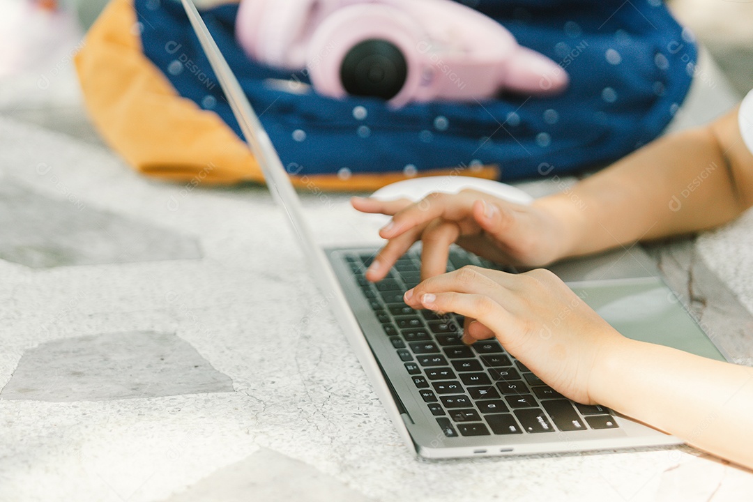 Garotinha sentada na mesa usando computador