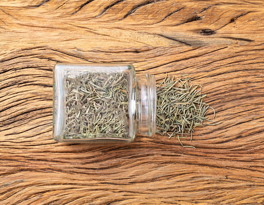Alecrim seco em um copo sobre a mesa de madeira