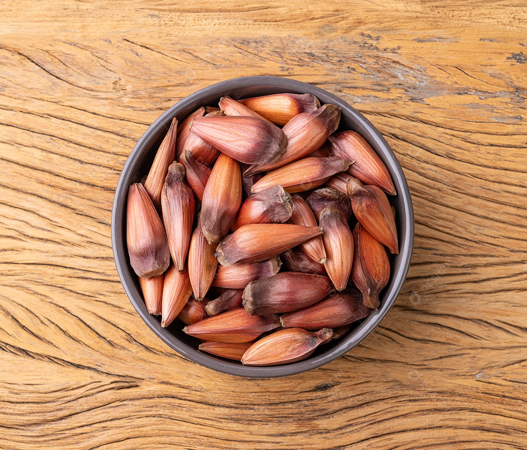Pinhões ou sementes de pinheiro em uma tigela sobre a mesa de madeira.