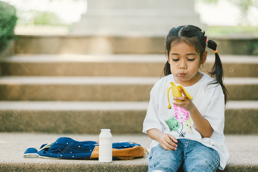 Menina sentada lanchando fruta