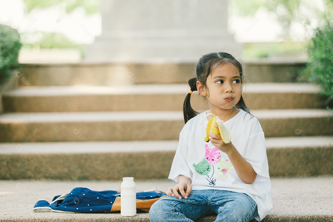 Menina sentada lanchando fruta