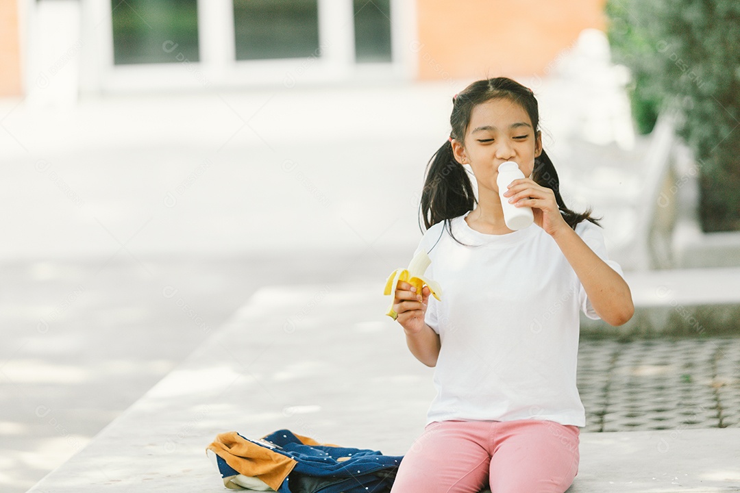 Menina sentada lanchando fruta