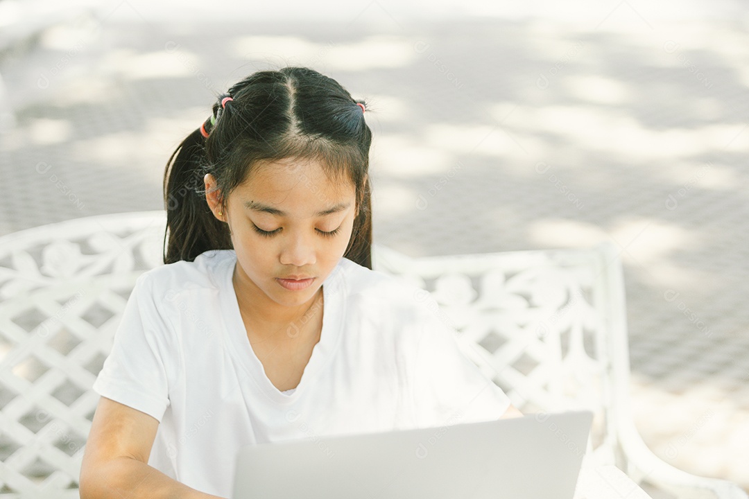 Menininha sentada usando laptop