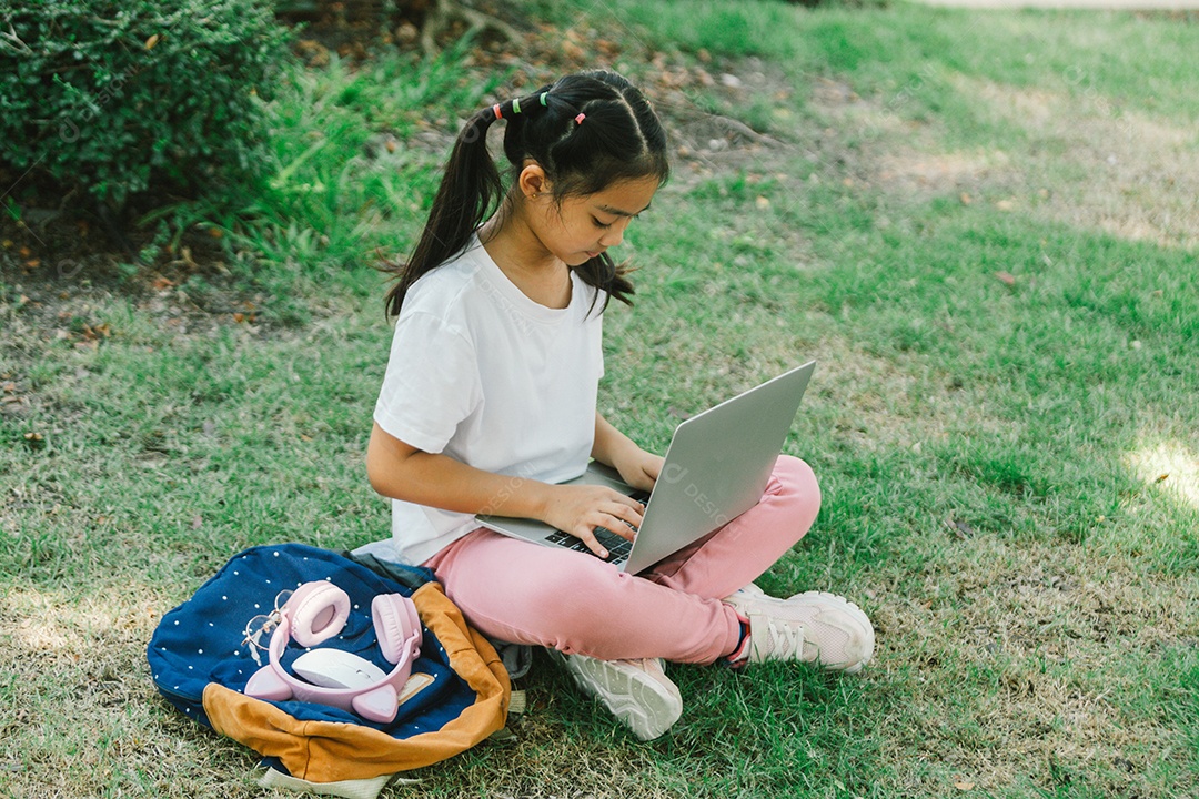 Menininha sentada usando laptop