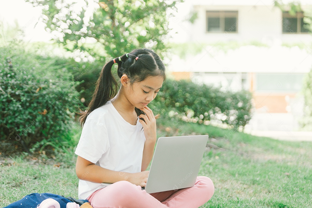 Menininha sentada usando laptop