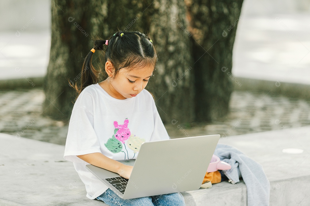 Menininha sentada usando laptop