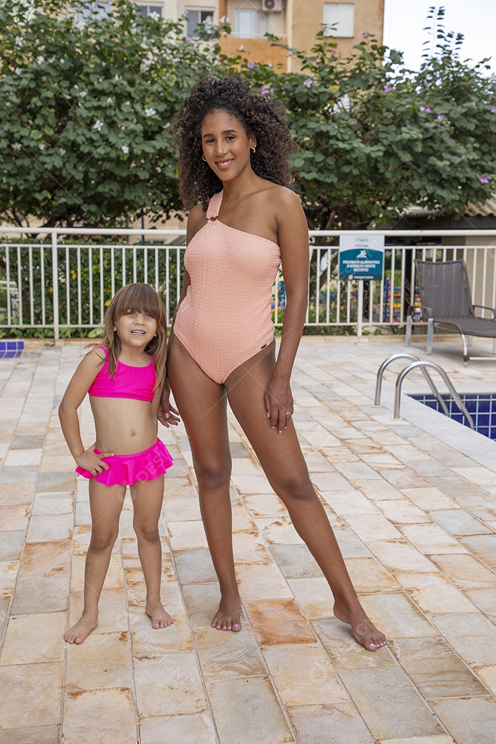 Linda mulher negra e garotinha pequena de maiô