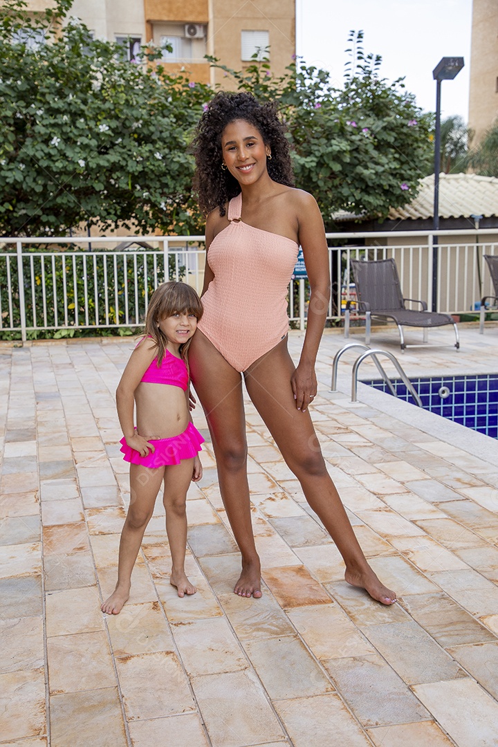 Linda mulher negra e garotinha pequena de maiô