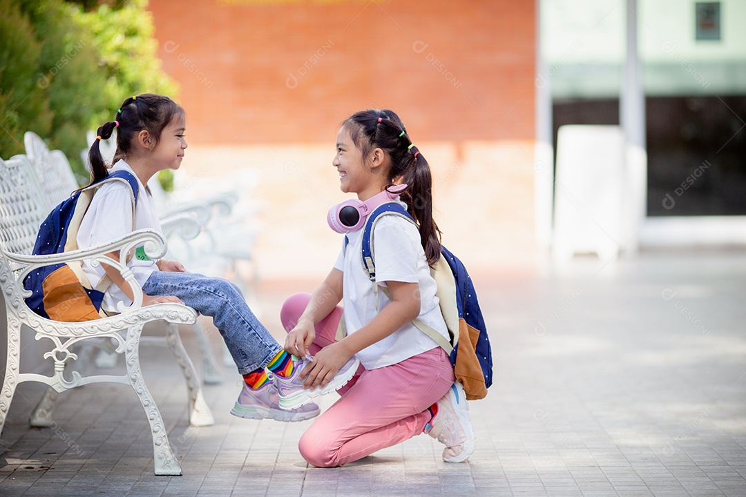 De volta à escola. Menina asiática lendo um livro. Alunos do ensino fundamental depois das aulas aprendendo lição de casa.