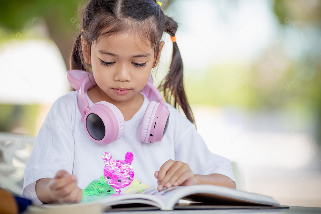 De volta à escola. Menina asiática lendo um livro. Alunos do ensino fundamental depois das aulas aprendendo lição de casa.