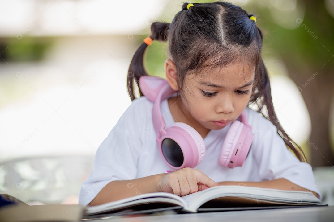 De volta à escola. Menina asiática lendo um livro. Alunos do ensino fundamental depois das aulas aprendendo lição de casa.