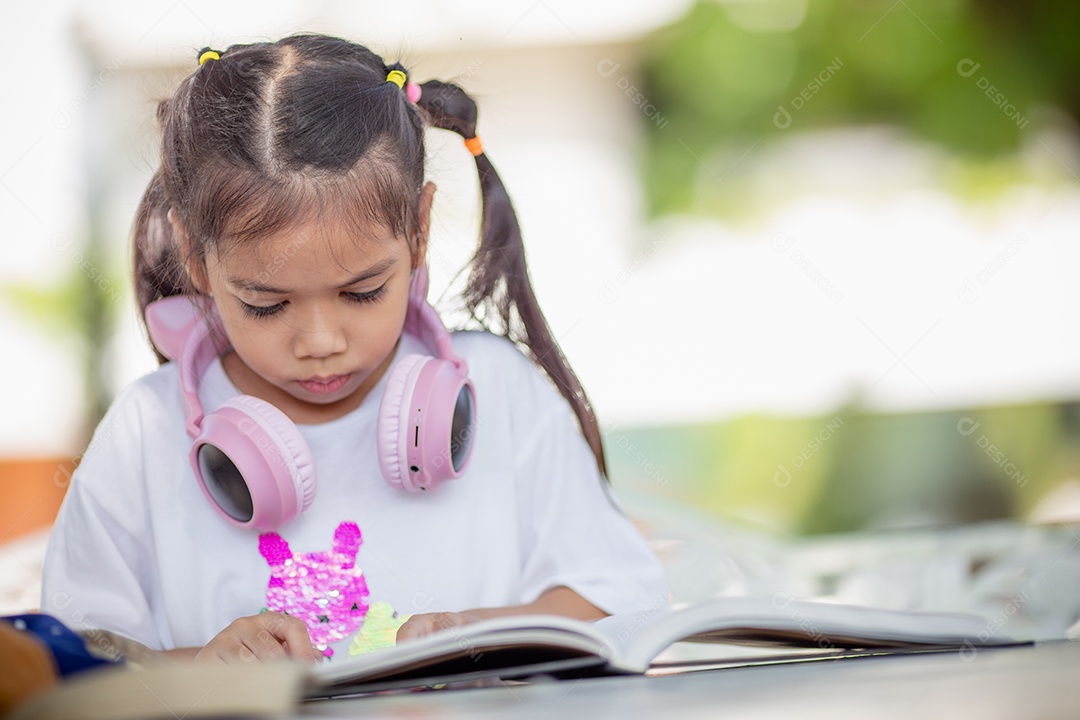 De volta à escola. Menina asiática lendo um livro. Alunos do ensino fundamental depois das aulas aprendendo lição de casa.