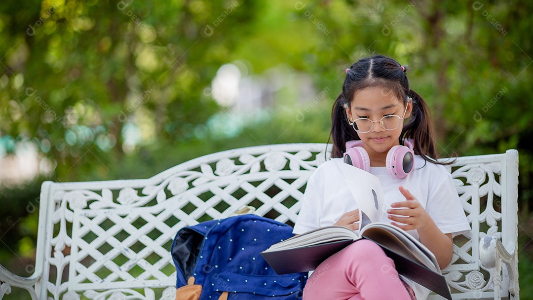 De volta à escola. Menina asiática lendo um livro. Alunos do ensino fundamental depois das aulas aprendendo lição de casa.