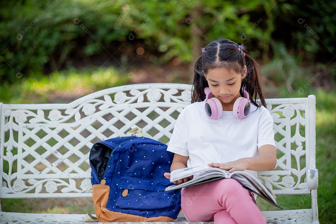 De volta à escola. Menina asiática lendo um livro. Alunos do ensino fundamental depois das aulas aprendendo lição de casa.