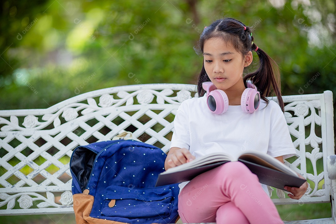 De volta à escola. Menina asiática lendo um livro. Alunos do ensino fundamental depois das aulas aprendendo lição de casa.