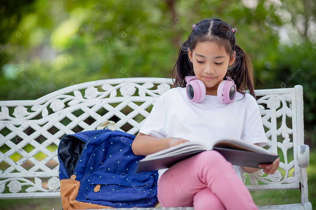 De volta à escola. Menina asiática lendo um livro. Alunos do ensino fundamental depois das aulas aprendendo lição de casa.