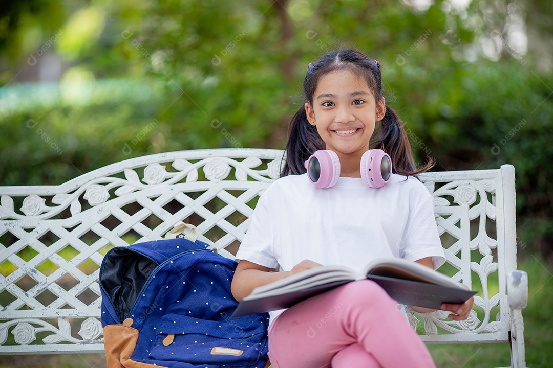 De volta à escola. Menina asiática lendo um livro. Alunos do ensino fundamental depois das aulas aprendendo lição de casa.