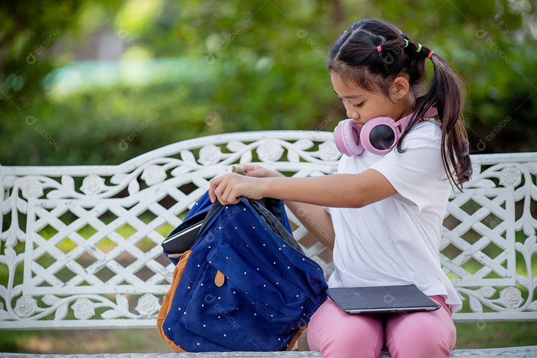 De volta à escola. Menina asiática lendo um livro. Alunos do ensino fundamental depois das aulas aprendendo lição de casa.