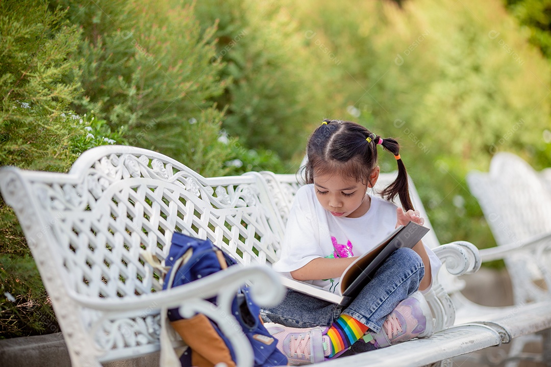 De volta à escola. Menina asiática lendo um livro. Alunos do ensino fundamental depois das aulas aprendendo lição de casa.
