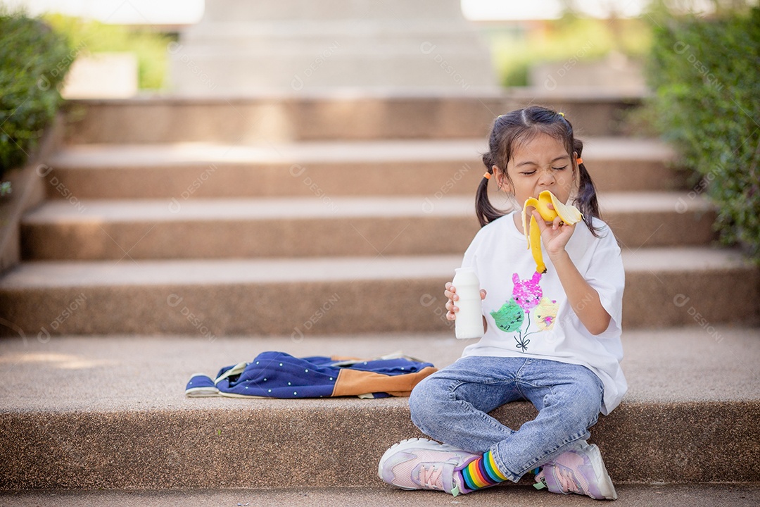 De volta à escola. Menina asiática lendo um livro. Alunos do ensino fundamental depois das aulas aprendendo lição de casa.