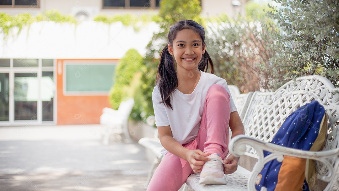 De volta à escola. Menina asiática lendo um livro. Alunos do ensino fundamental depois das aulas aprendendo lição de casa.