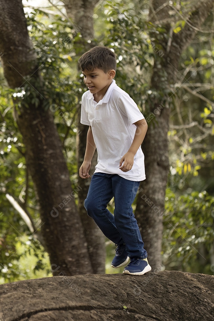 Menino de jeans azul e camiseta branca se divertindo ao ar livre