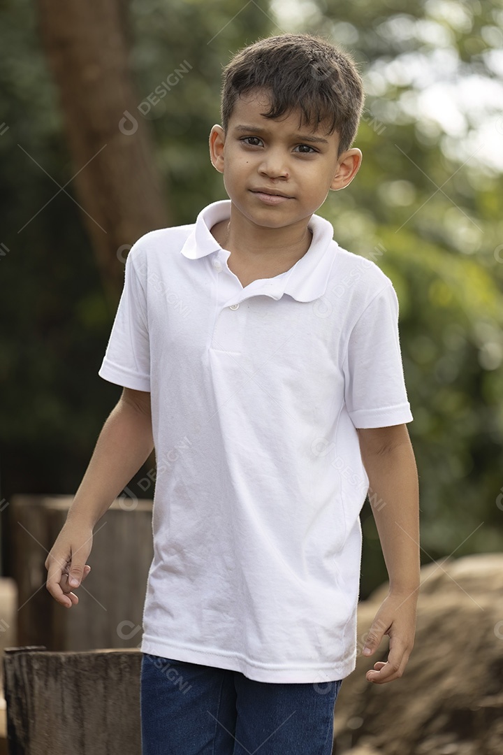 Menino de jeans azul e camiseta branca se divertindo ao ar livre